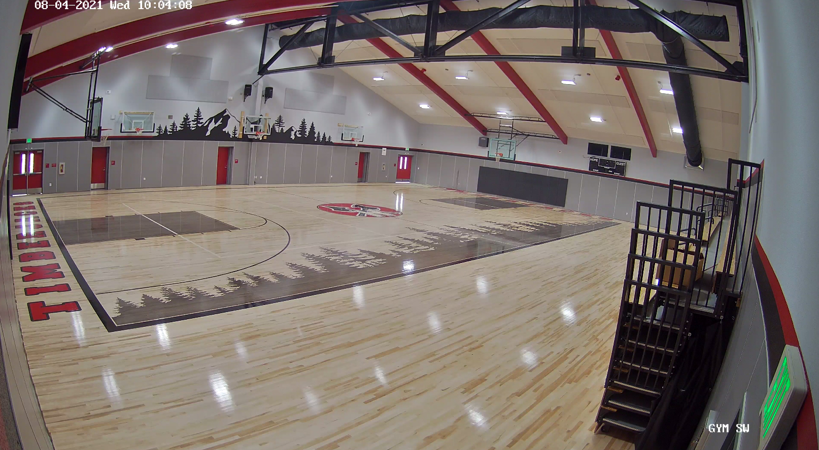 Finished gym interior, with forest art over side of basketball court and on wall by shot counter.