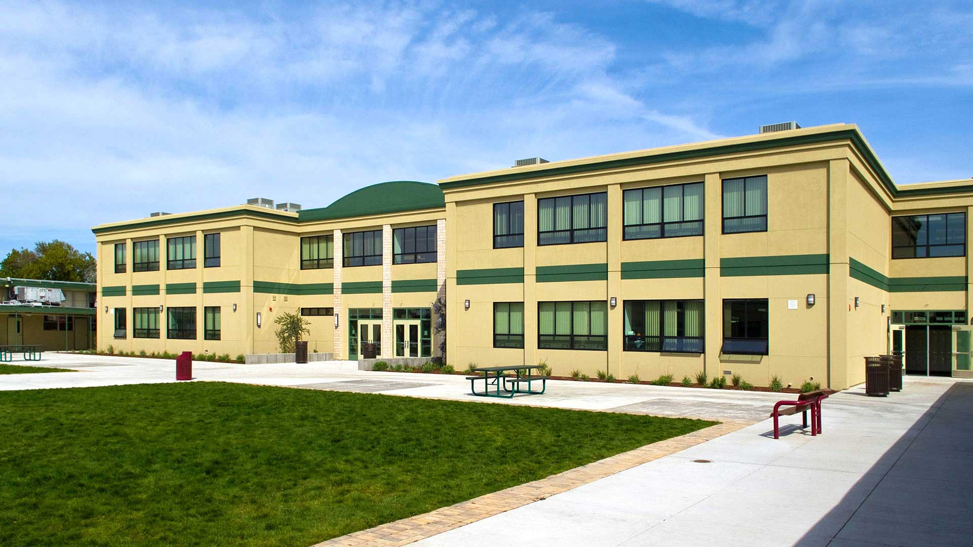 Two story modular classroom wing, beige walls with green details and large windows.